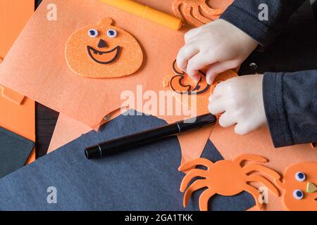 Small child doing autumn crafts at home, school or kindergarten. Halloween children party and diy concept. Stock Photo