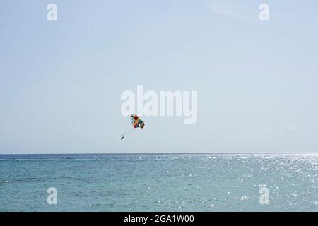 A tourist parasailing over the Caribbean Sea near the coast of Cozumel Island, Mexico Stock Photo