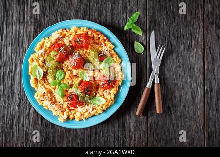 creamy tomato risotto with cherry tomatoes and sauce pesto on a blue plate, flat lay, free space Stock Photo