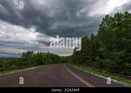 Dark storm clouds moving in on a mountaintop roadway. Stock Photo