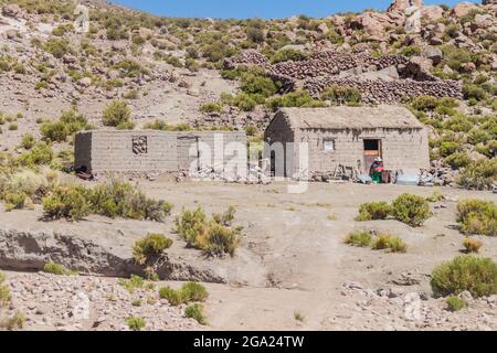 SOUTHWESTERN BOLIVIA - APRIL 16, 2015: Indiegenous woman sits at the adobe house in a small settlement, Stock Photo