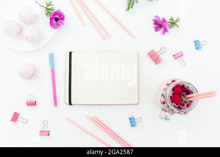 Smoothie with straws, marshmallow, anemones flowers and diary on white background. Flat lay. Stock Photo