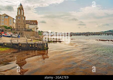 A view of Swanage wellington clock tower warped reflection in the glassy blue and brown sea Stock Photo