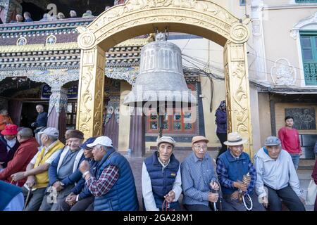 People sitting around a bell in the courtyard of the largest Tibetan Buddhist stupa in Nepal at Boudhanath in Kathmandu, Nepal Stock Photo