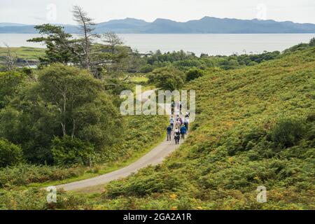 Tourists walk along a winding path on the Isle of Eigg, Scotland; Isle of Eigg, Scotland Stock Photo