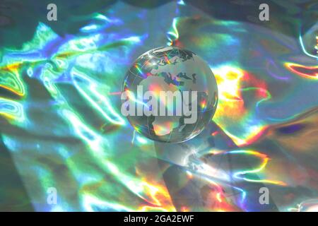Glass globe with reflective and rainbow on holographic background. Close up. Copy space. Stock Photo