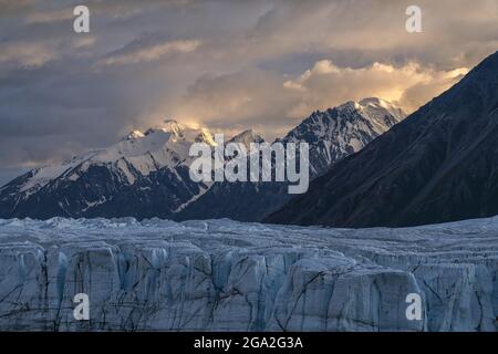 The vast Donjek Glacier in Kluane National Park with the sunset lighting up the clouds over the snowcapped mountaintops creating a stunning image, ... Stock Photo