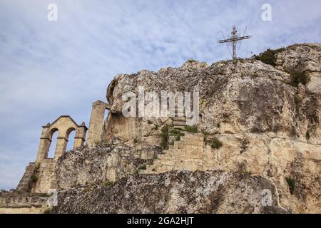 Christian cross and ruins on the rocky mountaintop; Matera, Basilicata, Italy Stock Photo