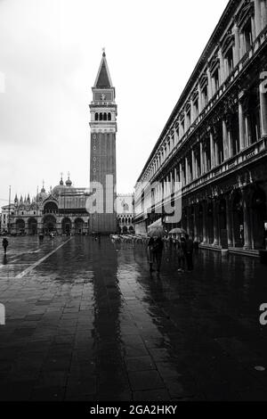 The iconic St Mark's Campanile and St Mark's Basilica in St Mark's Square with tourists sightseeing on a rainy day; Venice, Venezia, Italy Stock Photo