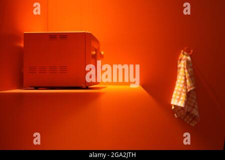 orange microwave at orange kitchen with white towel. technology concept - heating energy inside microwave oven. Stock Photo