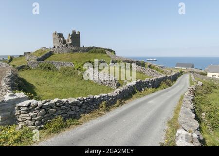 O'Brien's Castle on Inis Oirr (Inisheer), one of the Aran Islands with the expedition ship, the National Geographic Explorer, in the distance in Ga... Stock Photo