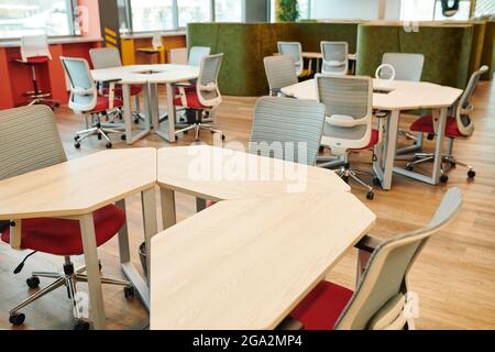 Interior of contemporary large open space office with many chairs by tables and along windowsills with no workers or managers around Stock Photo