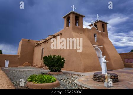 Side view of the historic San Francisco de Asis Church with a statue of San Francisco of Asis in the landscaped courtyard, located on the main plaz... Stock Photo