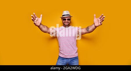 Young summer stylish muscular tattooed bearded man feels confident giving a hug to the camera Stock Photo