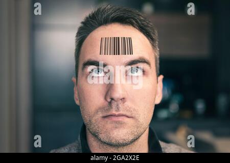 A man with a stupid expression looks at his qr code on his head. The concept of chipping the population. young man with a qr code on his forehead. glo Stock Photo