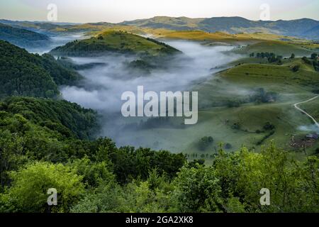 Morning mists in the valleys below Salciua in Sub Piatra of The Trascaului Mountains; Salciua, Sub Piatra, Transylvania, Romania Stock Photo