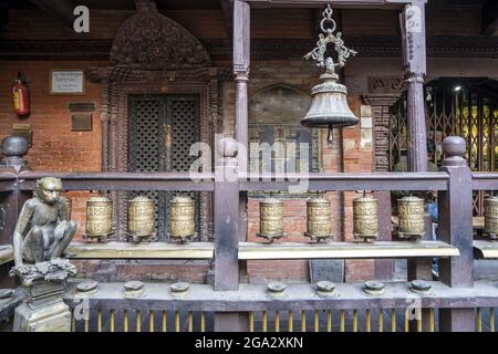 Brass monkey figure next to balcony with prayer wheels and bell in Kwa Bahal Golden Temple in the old city of Patan or Lalitpur built in the twelft... Stock Photo