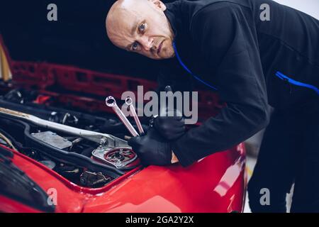 Man working in car service holding tools and wrench and showing ok sign Stock Photo