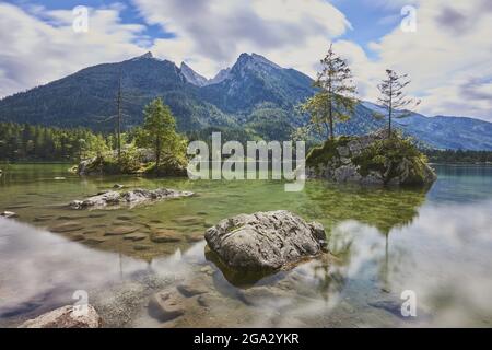 Norway spruce (Picea abies) tree on small, rock islands in the clear waters of Lake Hintersee, Bavarian Alps Stock Photo