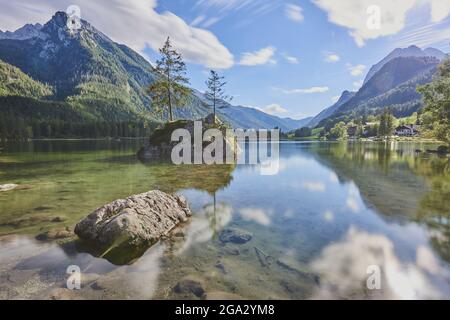 Norway spruce (Picea abies) tree on a small, rock island in the clear waters of Lake Hintersee, Bavarian Alps Stock Photo