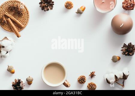 Autumn composition. Flat lay coffee cup, candles, cinnamon sticks, cones, acorns on white background. Nordic, hygge, cozy home concept Stock Photo