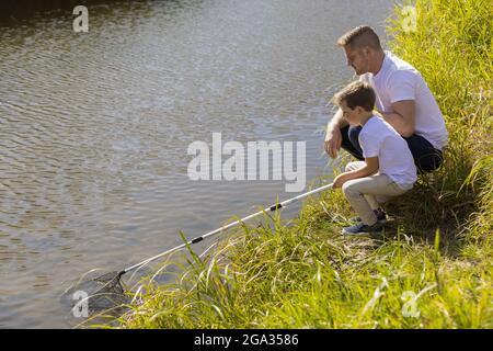 A father and son catching bugs in a stream in a city park during the fall season; Edmonton, Alberta, Canada Stock Photo