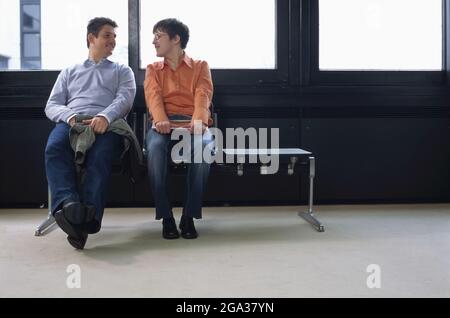 A special needs man and woman sit looking at each other in a flirting manner; Germany Stock Photo