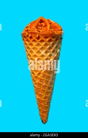 Vertical photo of caramel ice cream on light blue background. Stock Photo