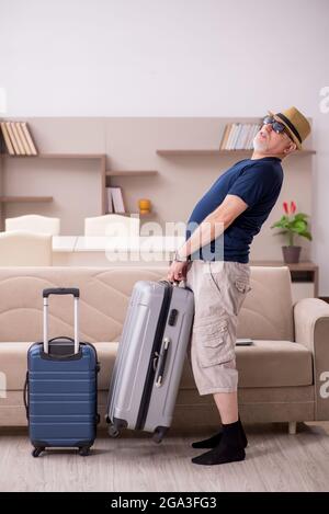 Old male tourist preparing for trip at home Stock Photo