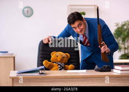 Young employee and his toy bear boss in funny concept Stock Photo