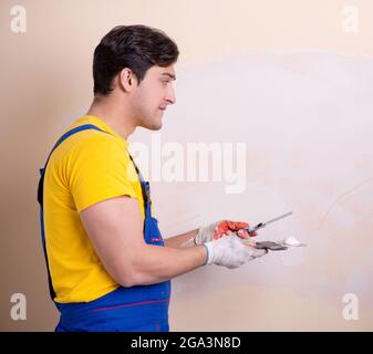 The young contractor employee applying plaster on wall Stock Photo