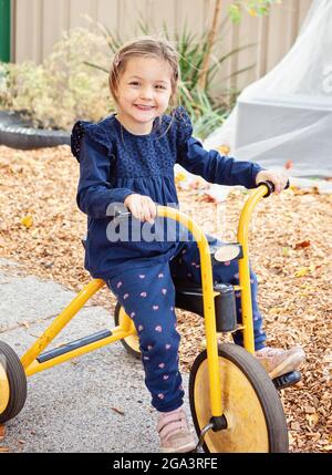 Happy child riding a tricycle on a path Stock Photo