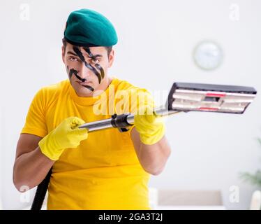 The funny man in military style cleaning the house Stock Photo