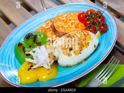 Photography of plate with sepia fried on a grill with pepper, boiled batat and honey-mustard sauce Stock Photo