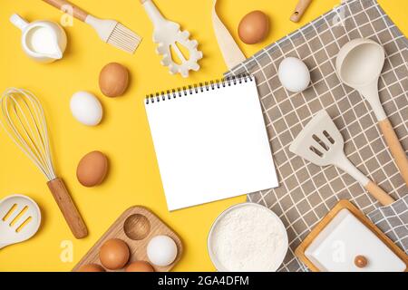 Baking ingredients, cooking utensil and open notebook on yellow background. Template for cooking recipes or your design. Top view Flat lay Mockup. Stock Photo