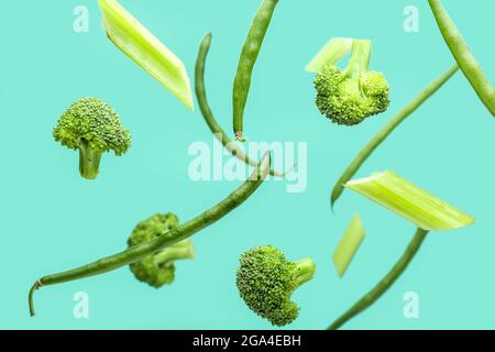 Flying green vegetables on color background Stock Photo