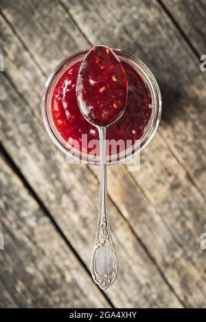 Red rasberries jam in jar on wooden table. Top view. Stock Photo
