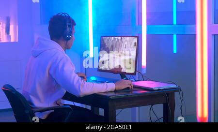 Back of pro gamer playing first person shooter video game on professional  computer for cyber esport competition. Pro player talking with multiple  players using headset during online tournament Stock Photo - Alamy