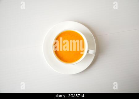 Pumpkin smoothie, spice latte. Boozy cocktail in white cup on white background. Autumn seasonal hot drinks. Thanksgiving day. Top view Stock Photo