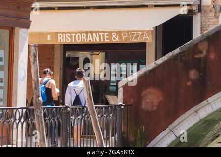 VENICE, ITALY - JUNE 15, 2016 tourists on narrow Venetian streets. Signboard Ristorante&Pizza in front of them Stock Photo