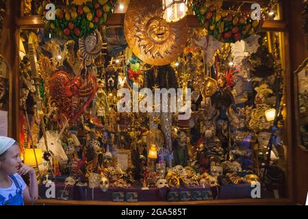VENICE, ITALY - JUNE 15, 2016 girl looking on masks on storefront with decorations, masks and souvenirs Stock Photo