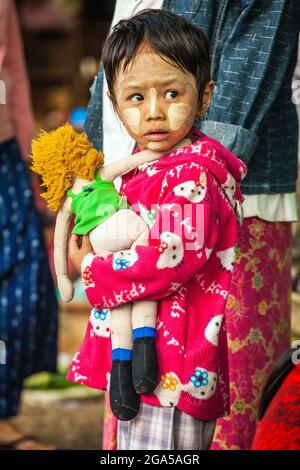 Cute Burmese child with thanaka face powder carrying rag doll, Hsipaw, Myanmar Stock Photo