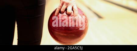 Woman throwing red bowling ball on lane closeup Stock Photo