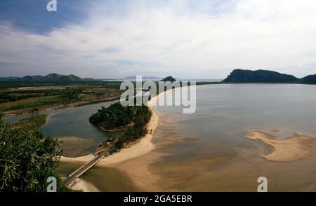 Thailand: Ao Bang Nang Rom (Bang Nang Rom Bay), part of Prachuap Bay, seen from Khao Chong Krajok (Mirror Mountain), Prachuap Khiri Khan Province. In historical terms, Prachuap is significant as one of the seven landing points where Imperial Japanese troops stormed ashore in 1941, on their way south to occupy Malaya and Singapore. The town is ringed on the land side with rugged limestone mountains, one of which – Khao Chong Krajok, or ‘mirror tunnel mountain’ – is pierced with a natural opening that appears not unlike a giant mirror, and which is perhaps the town’s most famous natural landmark Stock Photo