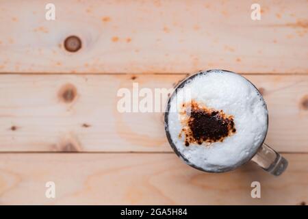 Top view of iced coffee froth in coffee mug cup on wooden floor. Stock Photo