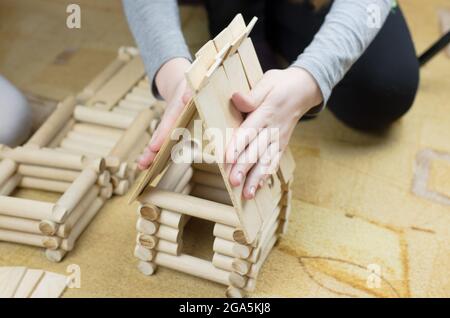 Girl builds a hut from wooden logs, children's wooden constructor Stock Photo