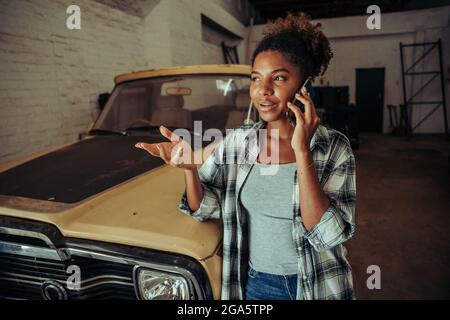 Mixed race female chatting to colleagues on cellular device after long day of work  Stock Photo