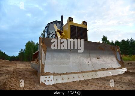 Dozer during clearing forest for construction new road . Yellow Bulldozer at forestry work Earth-moving equipment at road work, land clearing, grading Stock Photo