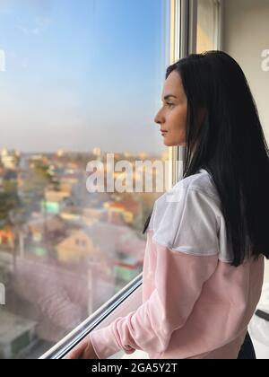Young woman watching through the window. Brooding woman and cityscape Stock Photo