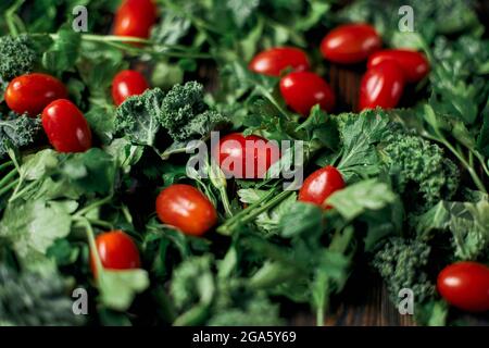 fresh tomatoes and sprigs of parsley on a wooden table. Stock Photo